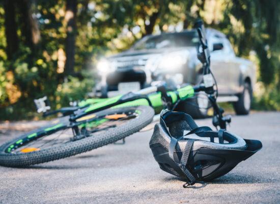 Close-up of a bicycling helmet fallen on the asphalt next to a bicycle after car accident on the road. Conceptual of accident car crash with bicycle on road.