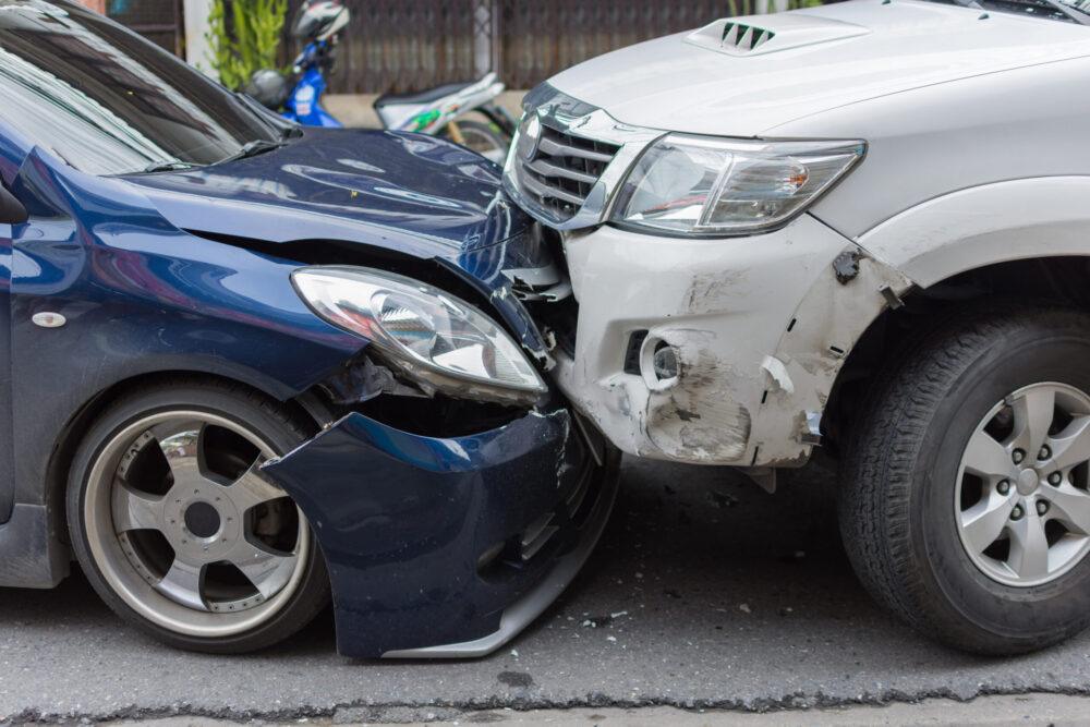 Car crash from car accident on the road in a city between saloon versus pickup wait insurance.