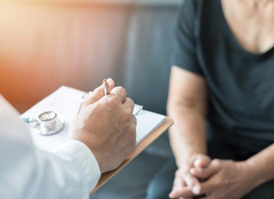 Geriatric doctor (geriatrician) consulting and diagnostic examining elderly senior adult patient (older person) on aging and mental health care in medical clinic office or hospital examination room