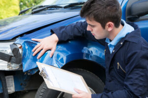Auto Workshop Mechanic Inspecting Damage To Car And Filling In R | Stag Liuzza Auto Workshop Mechanic Inspecting Damage To Car And Filling In Repair Estimate
