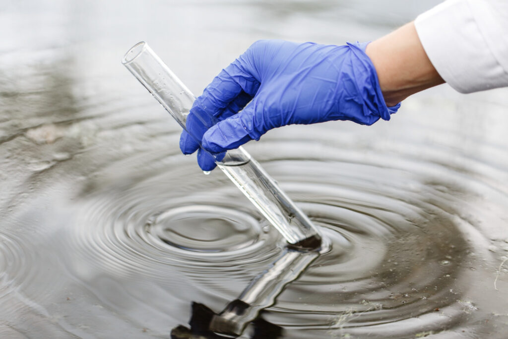 scientist taking sample of contaminated water using a clear vial