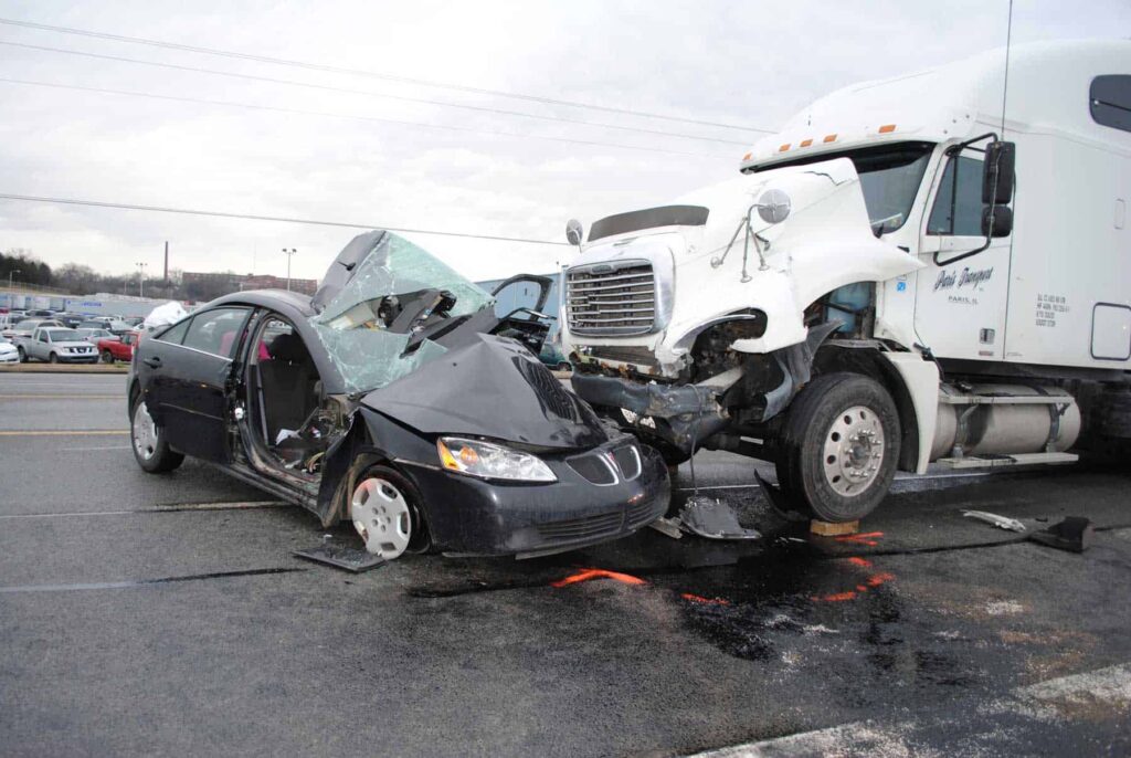 A commercial semi truck crashed into a small black car