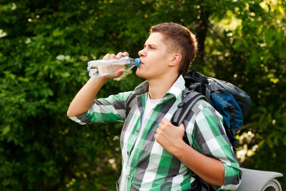 man drinking from plastic water bottle
