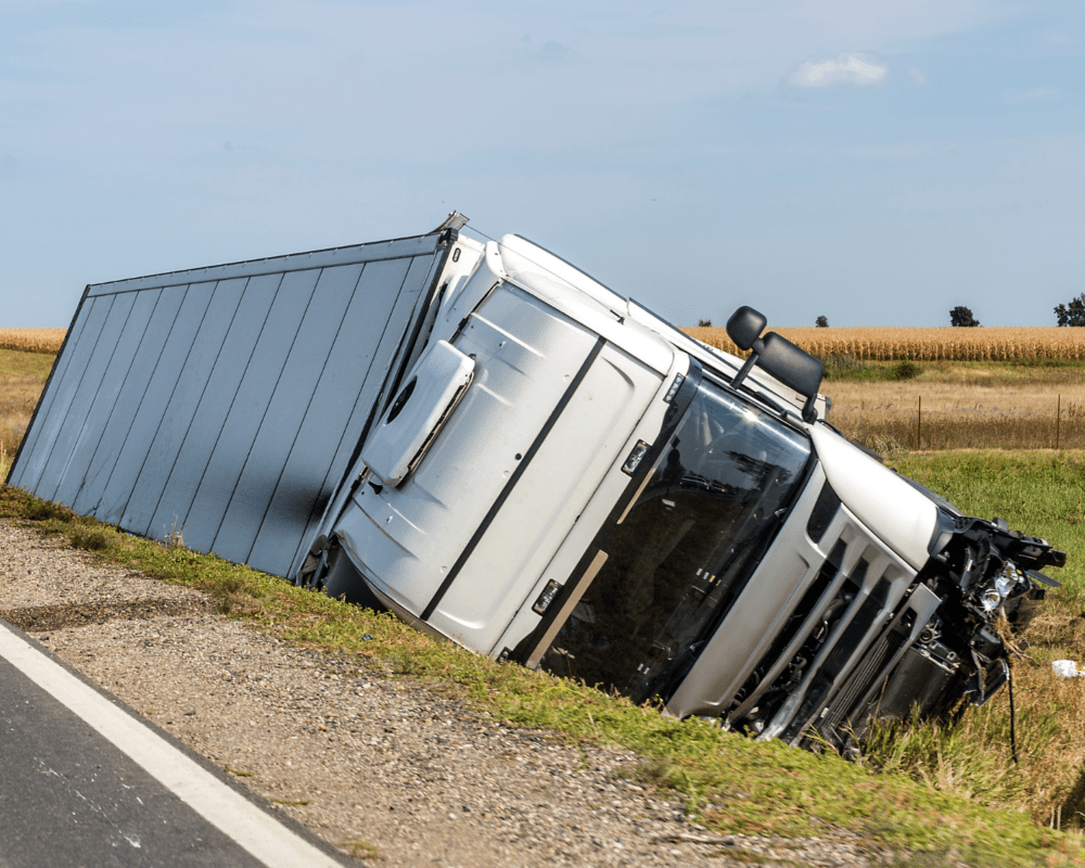 A white 18-wheeler truck stuck in a ditch following a truck accident