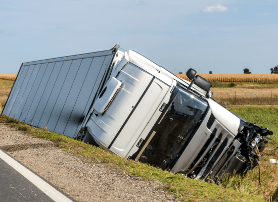 A white 18-wheeler truck stuck in a ditch following a truck accident