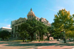 photo of a courthouse behind a row of trees